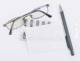 Glasses and tablets. White sheet with a ballpoint pen