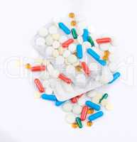 Tablets and capsules in blister packs on white background