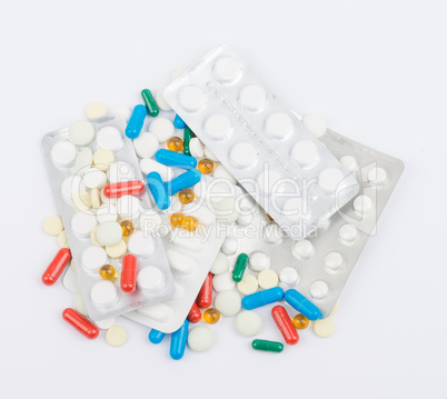 Tablets and capsules in blister packs on white background