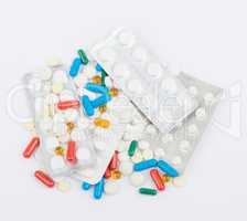 Tablets and capsules in blister packs on white background