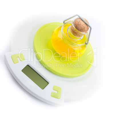 Bottle of olive oil stands on kitchen electronic scales