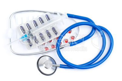 Stethoscope and pills with white sheet of paper