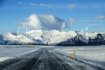 Snowy road with volcanic mountains in wintertime