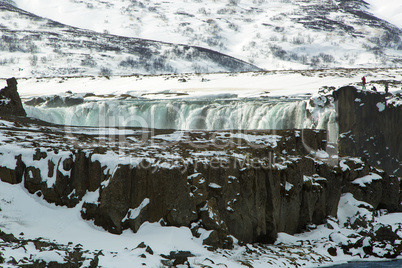 Tourists at the Icelandic waterfall Godafoss in wintertime