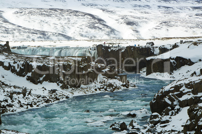 Tourists at the Icelandic waterfall Godafoss in wintertime