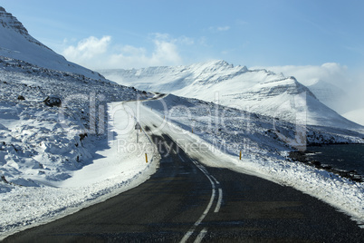 Snowy and icy road with volcanic mountains in wintertime