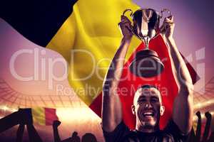 Composite image of portrait of successful rugby player holding t