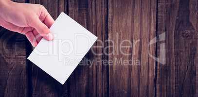 Hand holding paper against wooden wall
