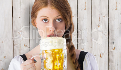 Composite image of oktoberfest girl drinking jug of beer