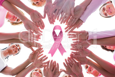 Composite image of happy women in circle wearing pink for breast