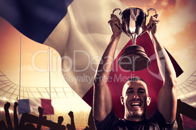 Composite image of portrait of successful rugby player holding t