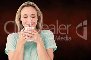 Composite image of cheerful blonde holding mug of hot drinking