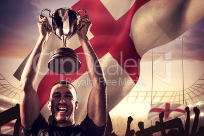 Composite image of portrait of successful rugby player holding t