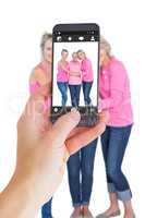 Composite image of female hand holding a smartphone