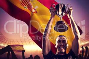 Composite image of portrait of successful rugby player holding t