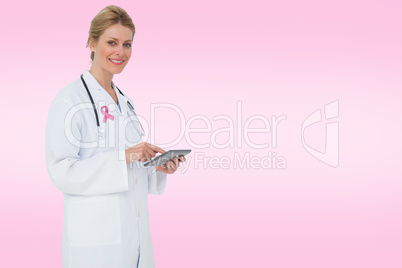 Composite image of blonde doctor using tablet pc