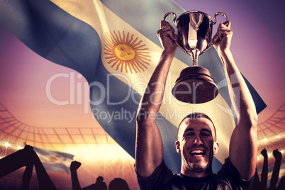 Composite image of portrait of successful rugby player holding t