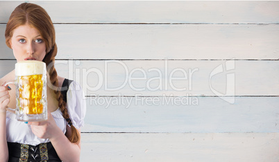 Composite image of oktoberfest girl drinking jug of beer