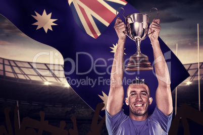 Composite image of portrait of smiling rugby player holding trop