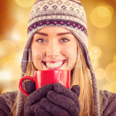 Composite image of happy blonde in winter clothes holding mug