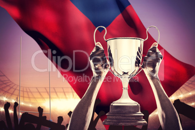 Composite image of cropped hand of athlete holding trophy