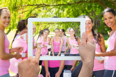 Composite image of hand holding tablet pc