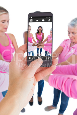 Composite image of female hand holding a smartphone