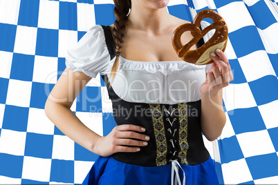 Composite image of pretty oktoberfest girl holding pretzel
