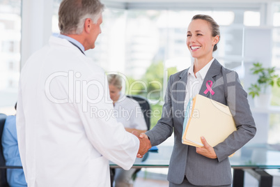Composite image of confident doctor greeting pretty businesswoma