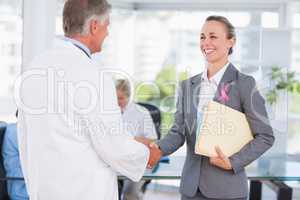 Composite image of confident doctor greeting pretty businesswoma