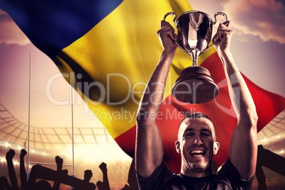 Composite image of portrait of successful rugby player holding t