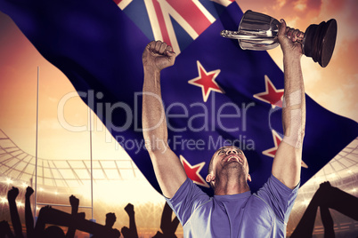 Composite image of happy rugby player holding trophy