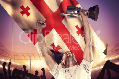 Composite image of happy rugby player holding trophy