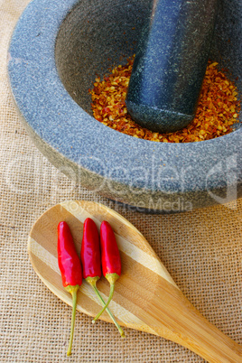 Getrocknete Chili im Mörser und Schoten auf Löffel