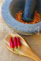 Getrocknete Chili im Mörser und Schoten auf Löffel