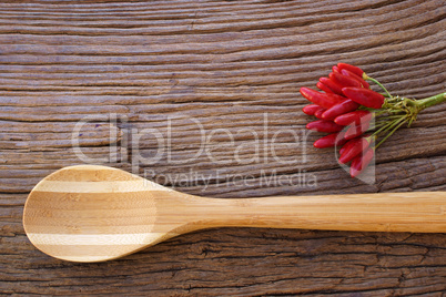 Bund reifer Chilischoten liegen mit Kochlöffel auf Holz