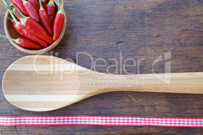 Schale mit frischen Chilischoten und ein Kochlöffel aus Holz