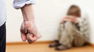 Angry man raised fist over wall corner sitting child boy