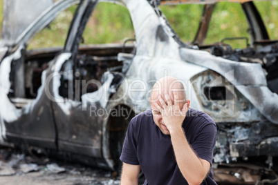 Crying upset man at arson fire burnt car vehicle junk