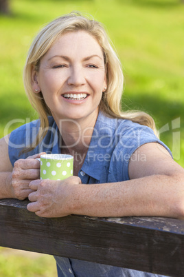 Woman Resting on Fence Drinking Tea or Coffee