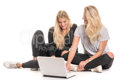 2 blonde Mädchen schauen gemeinsam in einen Laptop