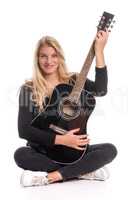 Junge Frau sitzt mit einer Gitarre im Schneidersitz