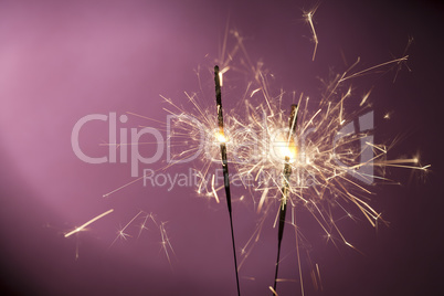 Burning sparklers on pink background