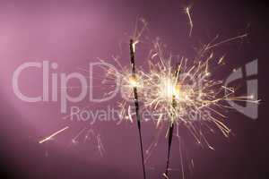 Burning sparklers on pink background