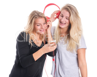 Zwei blonde Mädchen hören zusammen Musik über einen Kopfhörer