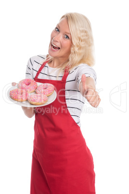 Hausfrau in Schürze hält einen Teller Donuts und zeigt Daumen hoch