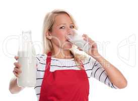Hausfrau in Schürze trinkt ein Glas frische Milch