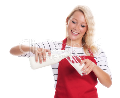 Hausfrau in Schürze gießt Frischmilch in ein Glas