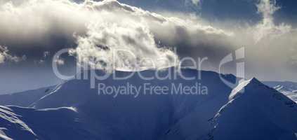 Panoramic view of mountains in sunset with sunlit clouds