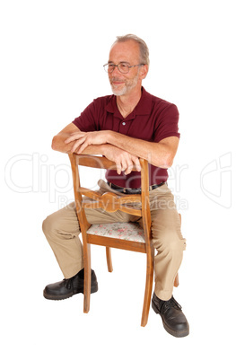 Middle age man sitting backwards on chair.